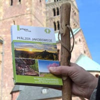 Beate Steger hält ihren Pilgerführer über die Pfälzer Jakobswege vor dem Dom in Speyer in der Hand